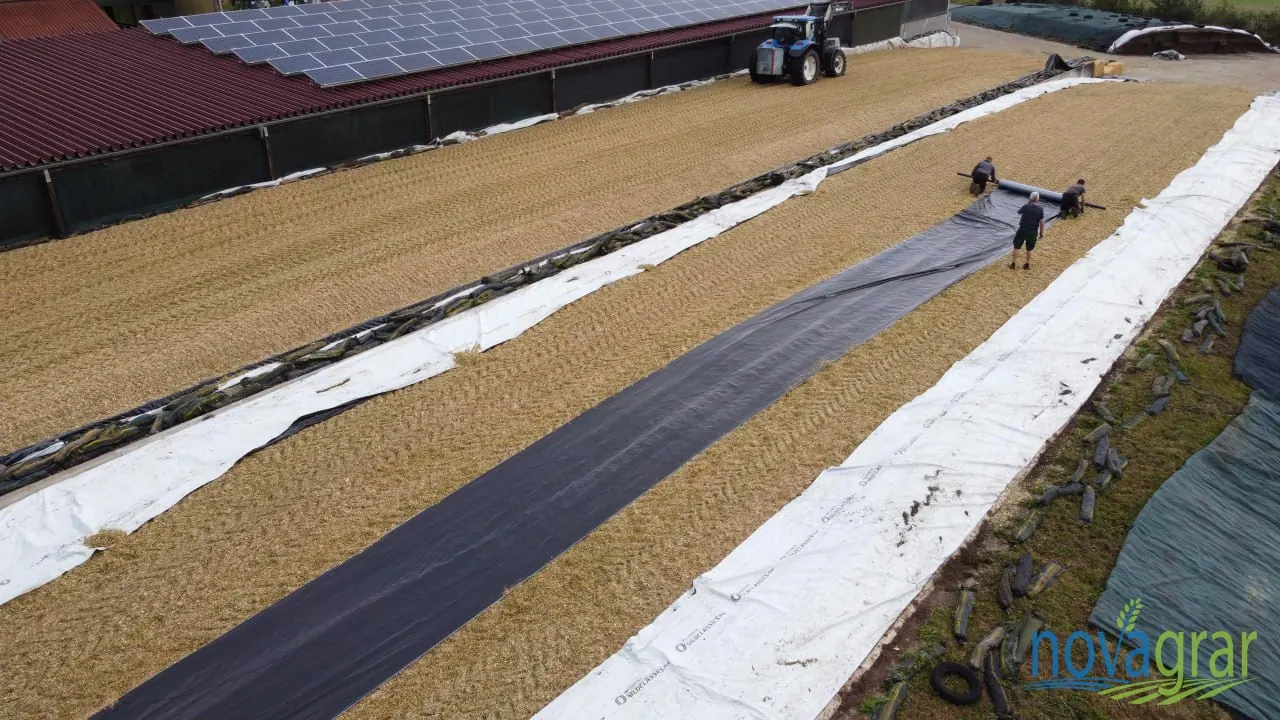 Deploying a barrier sheet over compacted silage